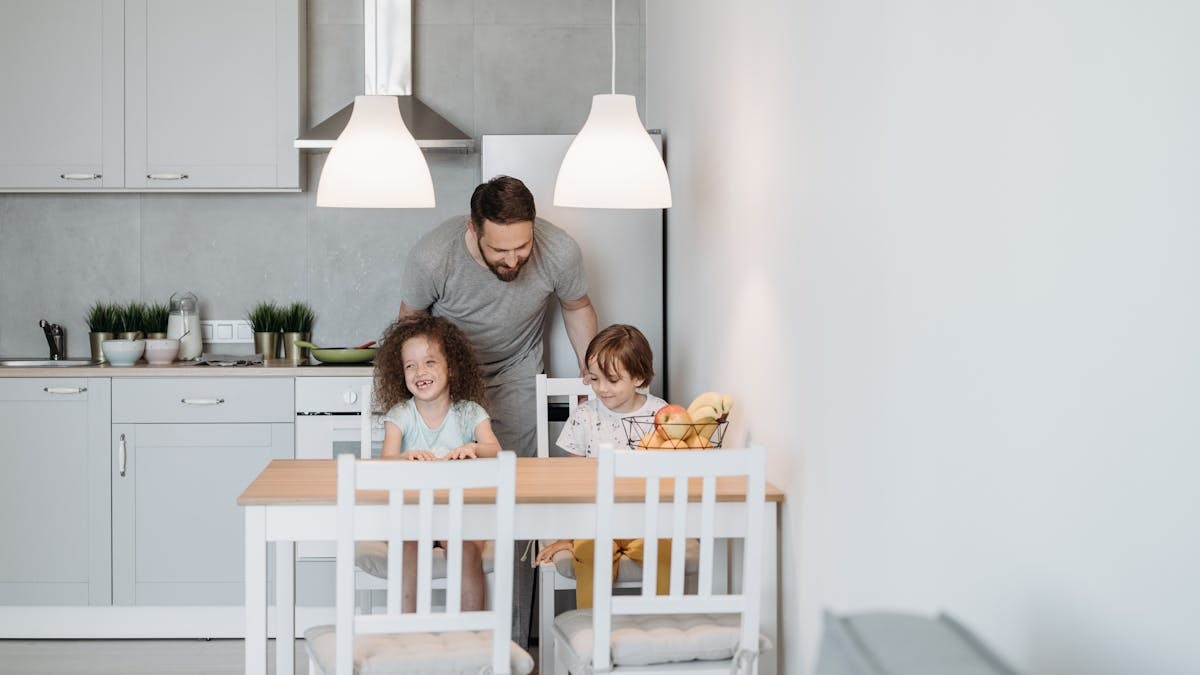 Father enjoying breakfast time with children in a modern kitchen dining area.